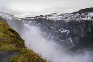 a view of a waterfall in a canyon with snow at Vogar Travel Service in Myvatn