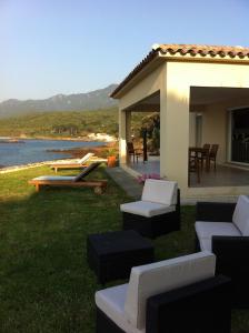a backyard with a house with chairs and a table at U capannellu in Calcatoggio