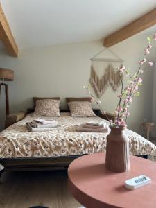 - une chambre avec un lit, une table et un vase avec des fleurs dans l'établissement Studio Cosy, à Castanet-Tolosan