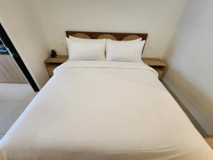een groot wit bed met 2 kussens in een kamer bij de' Asasta Apartment Benoa E216 in Nusa Dua +6 foto's