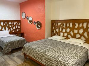 a bedroom with two beds and a red wall at Suitehome in Bahía de la Academia
