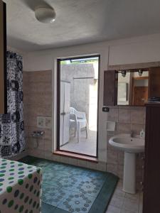 a room with a bathroom with a sink and a table at Da "Zia Giovanna" in San Giovanni Suèrgiu