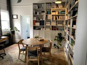 a room with a table and chairs and a book shelf at Light filled terrace flat in Sydney