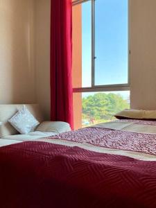 a bedroom with a bed and a window with red curtains at Top Rated Apartment with Parking and Full Comfort in Tarapoto