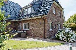 a brick house with a black roof at Haus Traumzeit Family in Braderup
