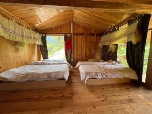 two beds in a room with wooden walls at Tả Mẩy Homestay in Lao Cai