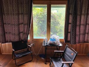 a room with two chairs and a table and a window at Tả Mẩy Homestay in Lao Cai