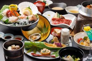 a table with plates of food and bowls of food at Shogetsu Grand Hotel in Jozankei