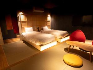 a room with two beds and a chair and a table at Nagasaki Sky Hotel in Nagasaki