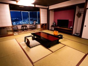 a living room with a table and a view of the city at Nagasaki Sky Hotel in Nagasaki