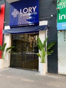 a store front with a blue awning and two plants at Lory Studio Hotel in São Paulo
