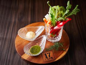 a wooden plate with a vase of flowers and vegetables at APA Hotel & Resort Osaka Namba Ekimae Tower in Osaka