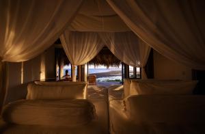 a bedroom with two beds and a window with curtains at Bo'a Vida Rote in Nembrala