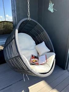 a wicker swing chair with books on it on a porch at Hidden Treasure in Mangawhai Village in Mangawhai