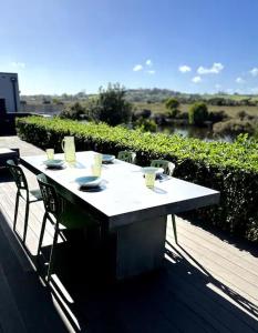 a table and chairs on a balcony with a view of a river at Hidden Treasure in Mangawhai Village in Mangawhai