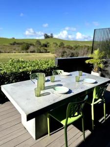 a table with plates and chairs on a patio at Hidden Treasure in Mangawhai Village in Mangawhai +39 photos