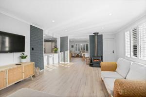 a living room with a white couch and a tv at Loganberry House - A Highlands home away from home in Bowral