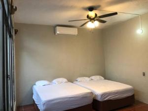 two beds in a room with a ceiling fan at casa jireh in Santa Cruz Huatulco