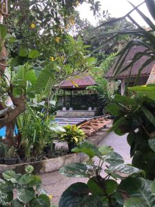 a garden with a bench and a gazebo at Santika Guest House in Ubud
