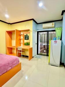 a bedroom with a bed and a refrigerator in it at โรงแรมกาญจนาสกลนคร in Sakon Nakhon