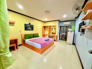 a bedroom with a bed and a refrigerator at โรงแรมกาญจนาสกลนคร in Sakon Nakhon