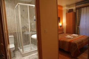 y baño con cama, ducha y lavabo. en Hostal Acella en Pamplona