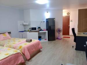 a bedroom with two beds and a desk and a refrigerator at K.NAT Room service in Nonthaburi