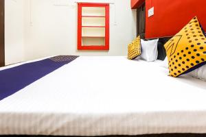 a large white bed with polka dot pillows on it at Hotel O Tirupati Guest House in Gwalior