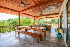 a patio with a wooden table and a couch at Tropical Villa Koh Tao in Ko Tao