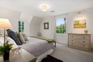 a bedroom with a bed and a dresser and windows at The Croft - Enchanting Bowral stone cottage in Bowral