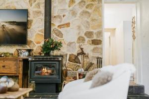 a living room with a stone wall with a fireplace at The Croft - Enchanting Bowral stone cottage in Bowral +22 photos