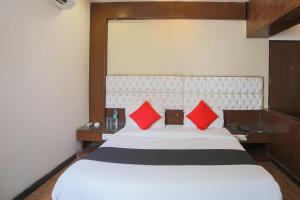 a bedroom with a large white bed with red pillows at Hotel O Arora shoppers park in Ghaziabad