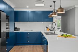 a blue kitchen with white counters and blue cabinets at Time2Reflect - the most relaxing Bowral getaway! in Bowral