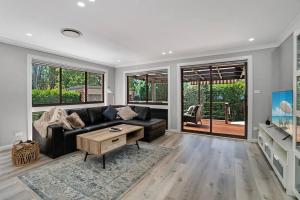 a living room with a black couch and a table at Teds Place Close to Bowral Town in Bowral