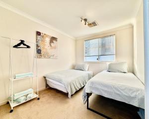 a bedroom with two beds and a window at Urban Oasis Townhouse East Perth in Perth