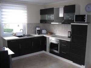 a kitchen with black cabinets and stainless steel appliances at Ferienwohnung Zwölf in Ueckeritz