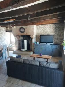 a living room with a couch and a tv at Maison chez l'habitant à 35 minutes du Futuroscope in Sossais