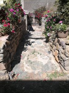 a stone pathway with flowers and a stone wall at INTERCULTURALITY LODGE Country House in Ollantaytambo