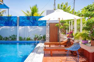 an umbrella and chairs next to a swimming pool at Hestia HaMy Beach House in Hoi An