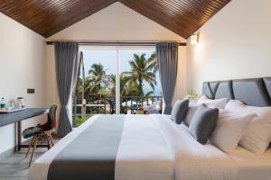 a bedroom with a large bed with a view of the ocean at Stone Wood Beach Resort, Vagator in Vagator
