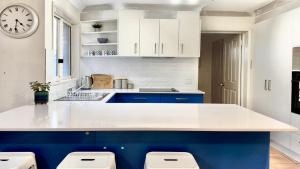 a kitchen with white and blue cabinets and a clock at Yamba Beach House in Yamba