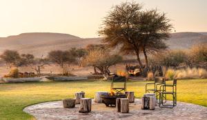 a group of chairs and a fire pit in a field at Okonjima Luxury Bush Camp in Otjiwarongo