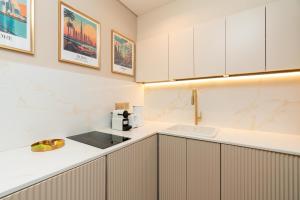 eine Küche mit weißen Schränken und einer Spüle in der Unterkunft Upgraded Designer-crafted Studio in JVC with Massive Terrace in Dubai