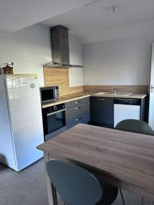 een keuken met een houten tafel en een witte koelkast bij Gîte de Villedavid in Amboise