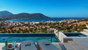 a swimming pool with chairs and a view of the ocean at Omega Residences in Karpathos