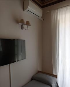 a bedroom with a flat screen tv and a window at Piccolo borgo antico Cefalù in Cefalù
