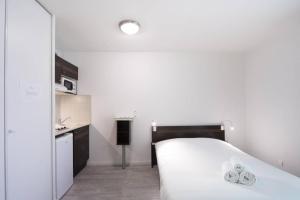 a white bedroom with a bed and a kitchen at Avisseau - Studio calme au coeur du quartier des Chartrons in Bordeaux