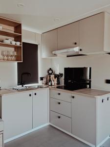 a white kitchen with white cabinets and a sink at Super Cordelia - Camping Belle-Vue in Berdorf
