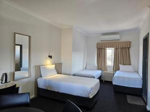 a hotel room with two beds and a mirror at Country Lodge Motor Inn in Bathurst +79 photos