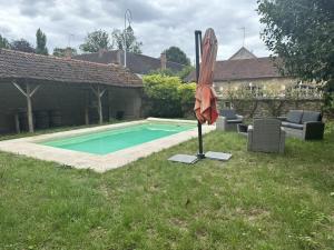 an umbrella sitting in the grass next to a swimming pool at La Maison du Chablisien in Chablis